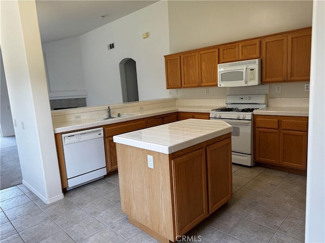 kitchen featuring white appliances, sink, a center island, kitchen peninsula, and tile countertops