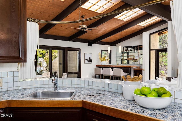 kitchen with ceiling fan, plenty of natural light, sink, and vaulted ceiling with beams