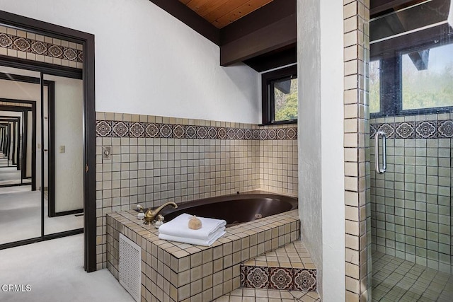 bathroom featuring beamed ceiling and shower with separate bathtub