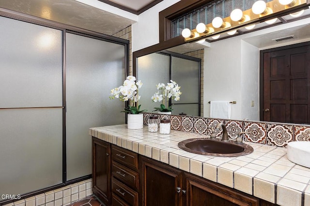 bathroom with a shower with shower door and vanity