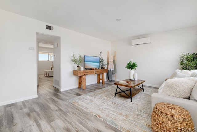 living room with an AC wall unit and light wood-type flooring