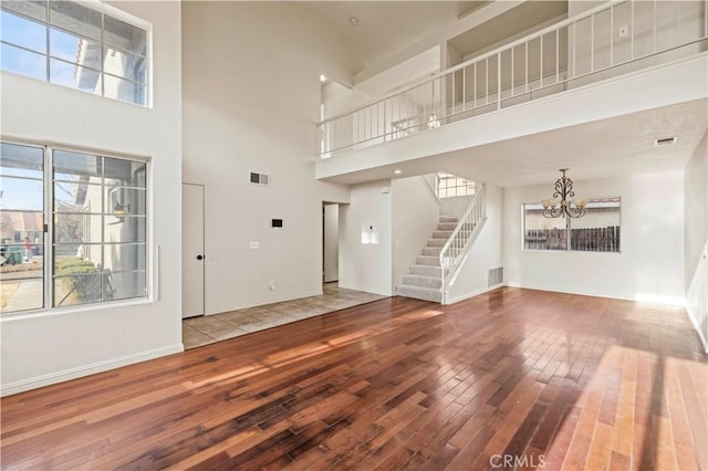 unfurnished living room with a high ceiling, hardwood / wood-style flooring, and a chandelier