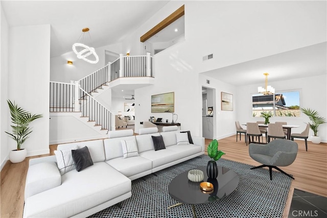 living room featuring a chandelier, wood-type flooring, and a high ceiling