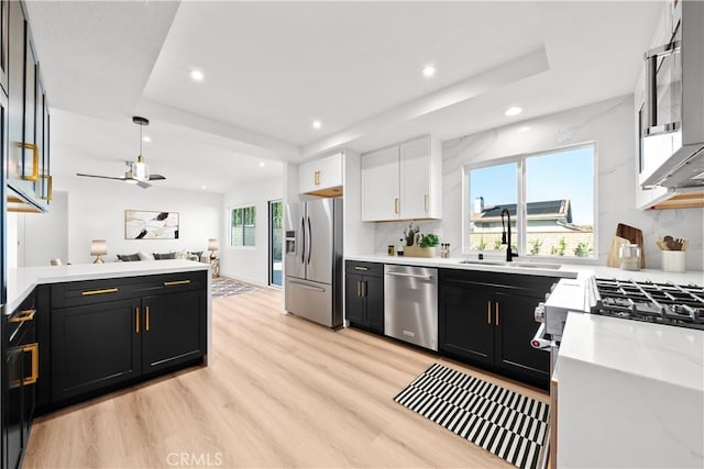 kitchen featuring white cabinetry, light wood-type flooring, sink, appliances with stainless steel finishes, and pendant lighting