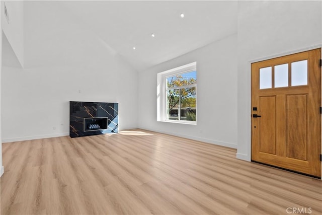 entrance foyer with high vaulted ceiling, a premium fireplace, and light hardwood / wood-style floors