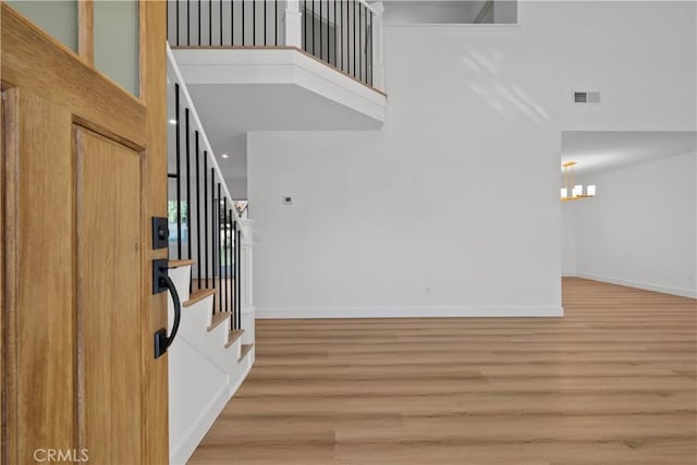 foyer featuring hardwood / wood-style floors, an inviting chandelier, and a towering ceiling