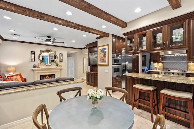 dining space featuring crown molding, recessed lighting, beamed ceiling, and a lit fireplace