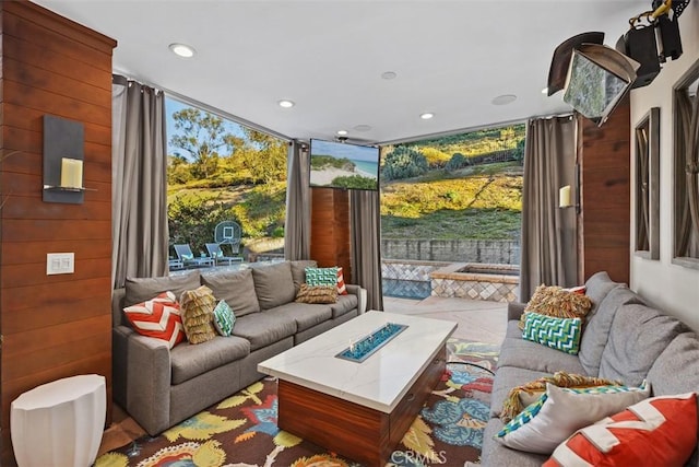 living area featuring wood walls, light tile patterned floors, a wall of windows, and recessed lighting