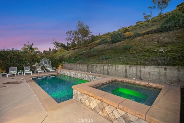 pool at dusk featuring a fenced in pool, a fenced backyard, a patio, and an in ground hot tub