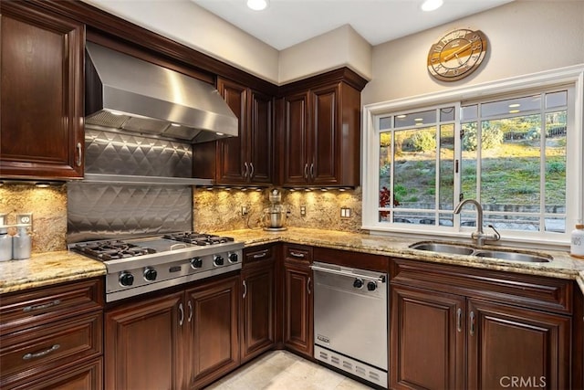 kitchen featuring a sink, appliances with stainless steel finishes, light stone countertops, wall chimney exhaust hood, and tasteful backsplash