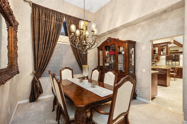 dining area featuring a towering ceiling, a notable chandelier, and light colored carpet