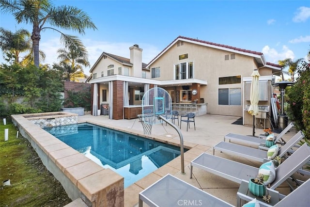 rear view of property with a patio, an outdoor pool, and stucco siding