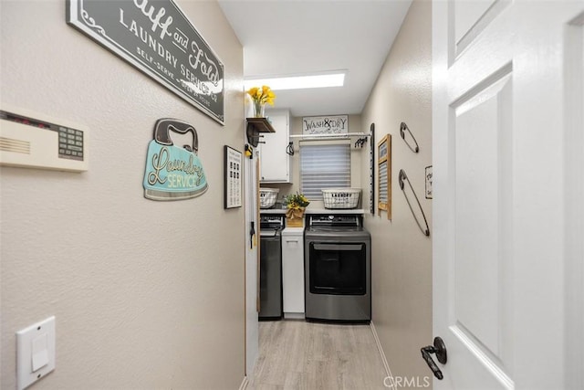 kitchen with baseboards, white cabinets, light countertops, light wood-style floors, and washing machine and clothes dryer