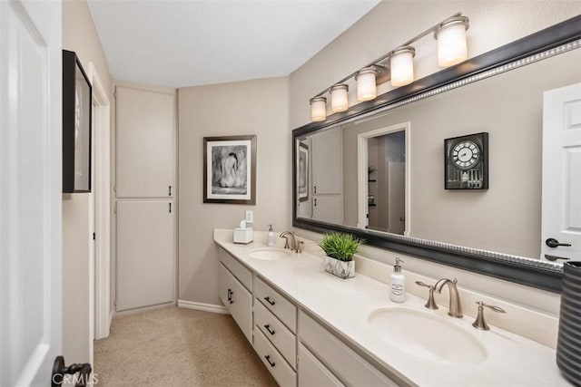 bathroom with carpet floors, double vanity, a sink, and baseboards