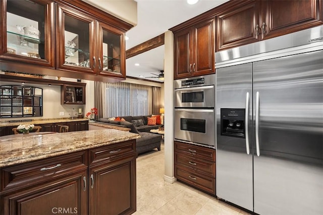 kitchen with ceiling fan, recessed lighting, appliances with stainless steel finishes, light stone countertops, and glass insert cabinets