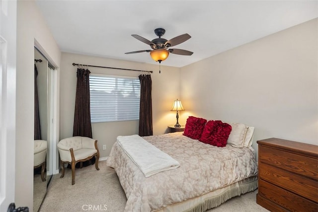 bedroom featuring a ceiling fan, a closet, light carpet, and baseboards