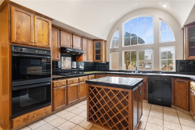 kitchen with black appliances, lofted ceiling, decorative backsplash, light tile patterned flooring, and a kitchen island