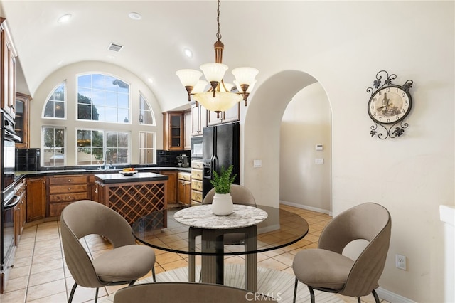 dining room featuring sink, lofted ceiling, a chandelier, and light tile patterned floors