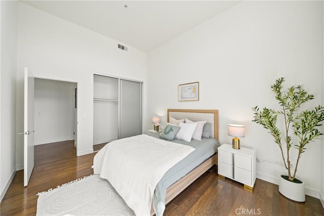bedroom with vaulted ceiling, baseboards, visible vents, wood finished floors, and a closet