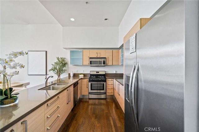 kitchen featuring a sink, light brown cabinetry, stainless steel appliances, a peninsula, and dark wood-type flooring