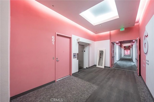 hallway with dark wood-style floors, a skylight, and elevator