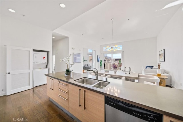 kitchen with stacked washer / drying machine, stainless steel dishwasher, open floor plan, light brown cabinets, and a sink