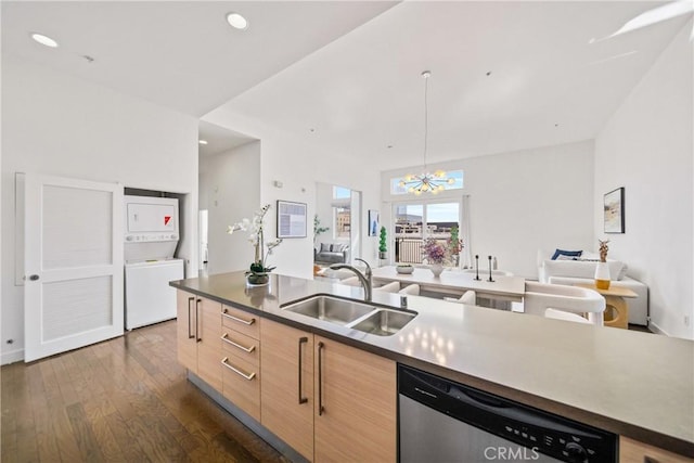 kitchen with stacked washer / drying machine, stainless steel dishwasher, a sink, a chandelier, and open floor plan