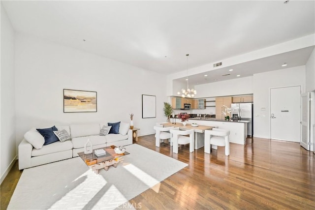 living room with an inviting chandelier, wood finished floors, and visible vents