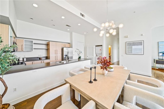 dining area with recessed lighting, a towering ceiling, dark wood-style floors, visible vents, and a notable chandelier