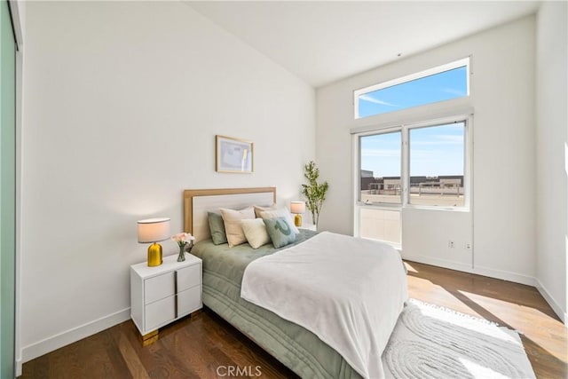 bedroom featuring a towering ceiling, baseboards, and dark wood-type flooring