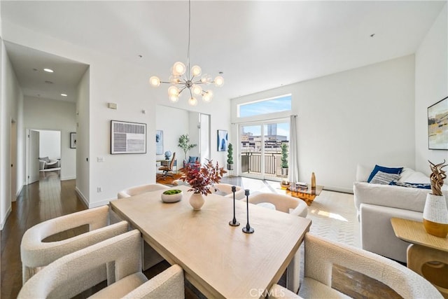 dining room with an inviting chandelier, a towering ceiling, dark wood finished floors, baseboards, and recessed lighting
