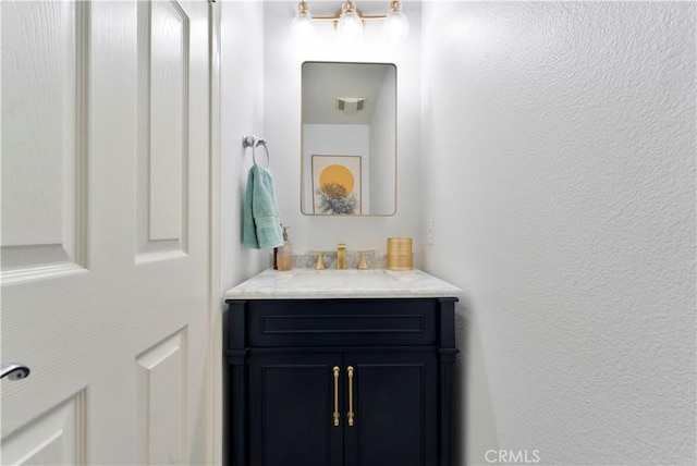 bathroom featuring a textured wall, visible vents, and vanity