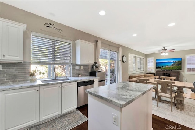 kitchen with a center island, open floor plan, white cabinetry, a sink, and dishwasher