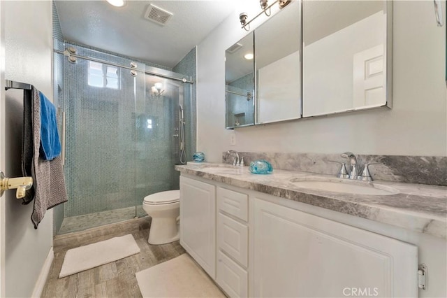 full bathroom with double vanity, visible vents, a sink, and wood finished floors