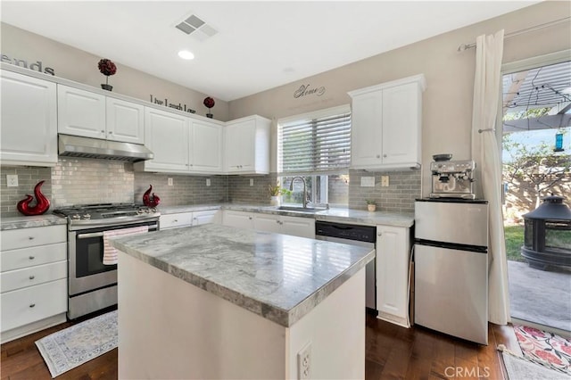 kitchen with appliances with stainless steel finishes, a center island, white cabinets, and under cabinet range hood