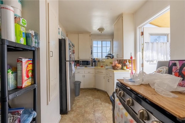 kitchen featuring a sink, white cabinetry, stainless steel appliances, and light countertops