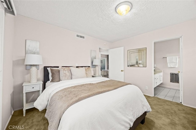 carpeted bedroom featuring a textured ceiling and ensuite bathroom