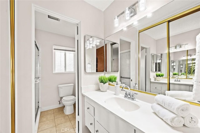 bathroom featuring tile patterned floors, toilet, vanity, and a shower with door