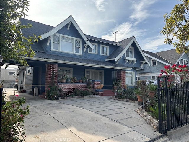 view of front facade featuring brick siding, a shingled roof, and fence