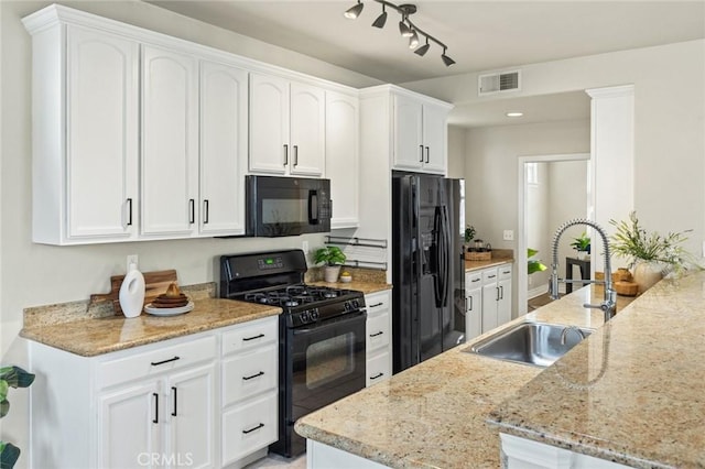 kitchen featuring a sink, light stone countertops, black appliances, white cabinetry, and visible vents