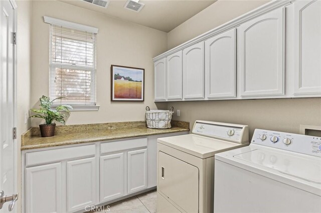 laundry room with washing machine and dryer, light tile patterned flooring, cabinet space, and visible vents