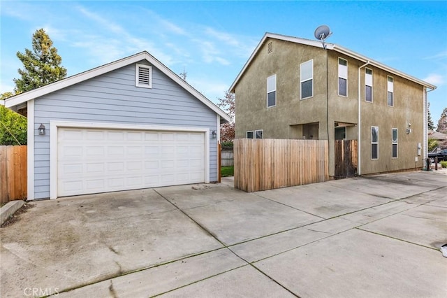 exterior space with stucco siding, an outdoor structure, a garage, and fence