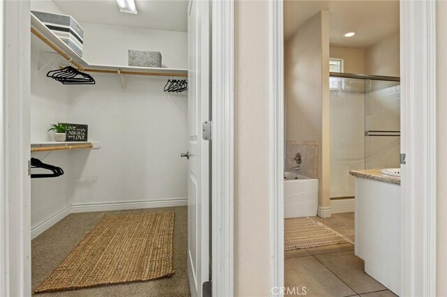 full bathroom with a walk in closet, an enclosed shower, a garden tub, and tile patterned flooring
