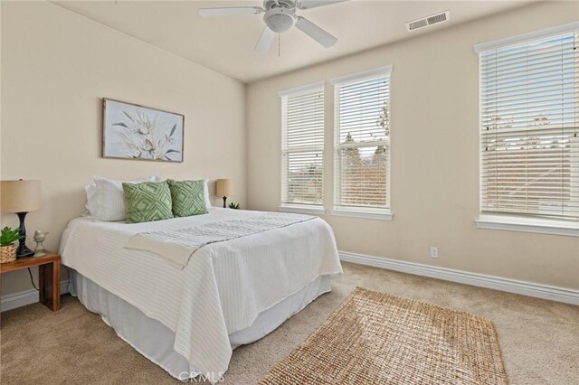 bedroom with visible vents, baseboards, a ceiling fan, and light carpet