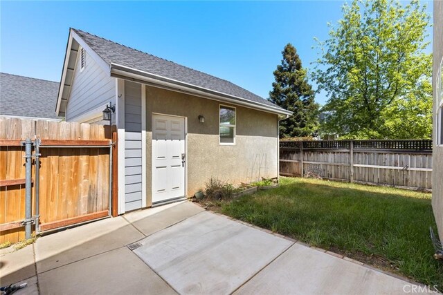 view of side of property featuring fence, a patio area, a lawn, and a shingled roof