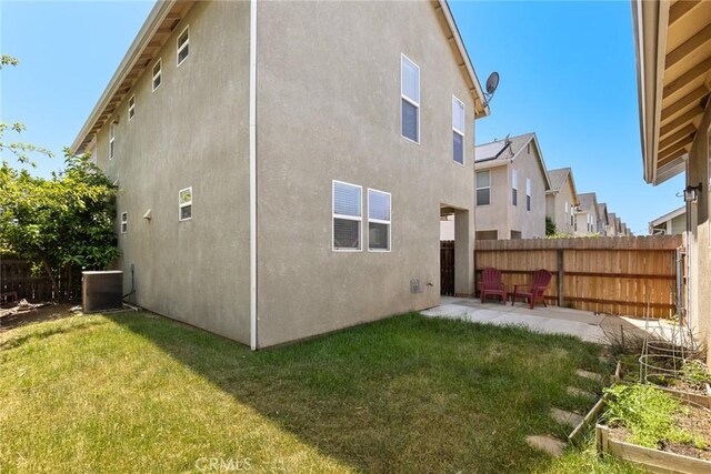 rear view of property with stucco siding, fence, a yard, and central AC unit