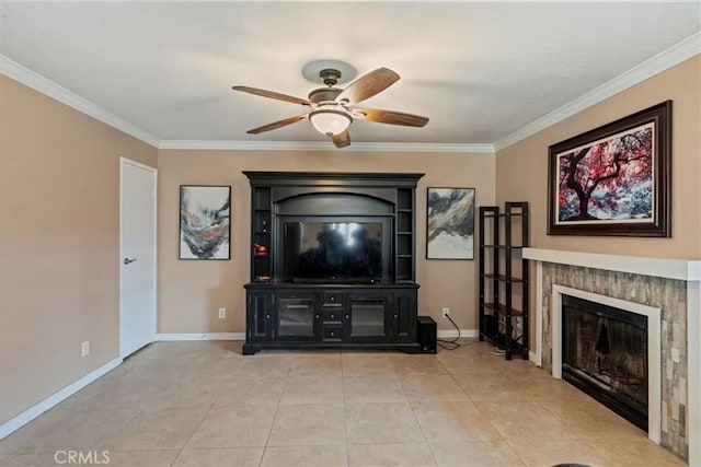 living room featuring a ceiling fan, ornamental molding, a glass covered fireplace, baseboards, and light tile patterned flooring