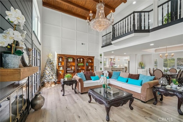 living room with an inviting chandelier, light wood-type flooring, a towering ceiling, wooden ceiling, and beam ceiling