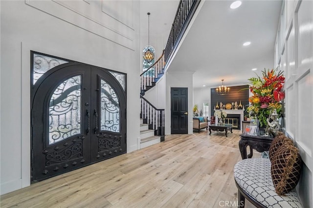 entrance foyer featuring light wood-type flooring, french doors, a chandelier, and a healthy amount of sunlight