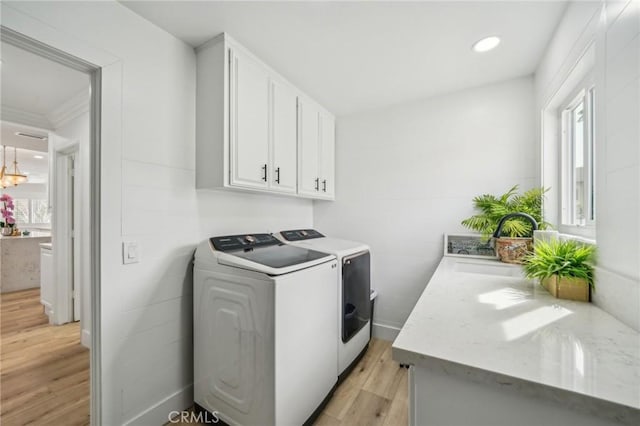 laundry room featuring sink, cabinets, washer and clothes dryer, and light hardwood / wood-style flooring